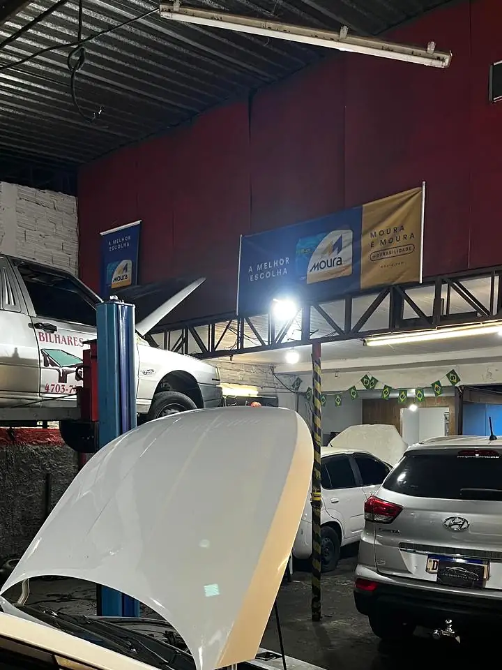 Interior da oficina da Automecânica Tico's, com veículos sobre elevador e capôs abertos durante manutenção